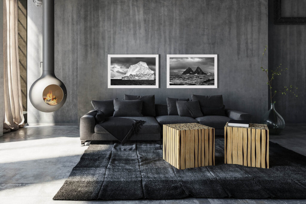 Minimalist industrial loft conversion living room with grey sofa and tables against grunge concrete walls warmed by a suspended fireplace with burning fire. Two Fine Art pictures on grey wall. Print on Fine Art paper